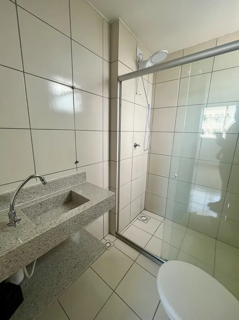 Banheiro com bancada em granito e box de vidro