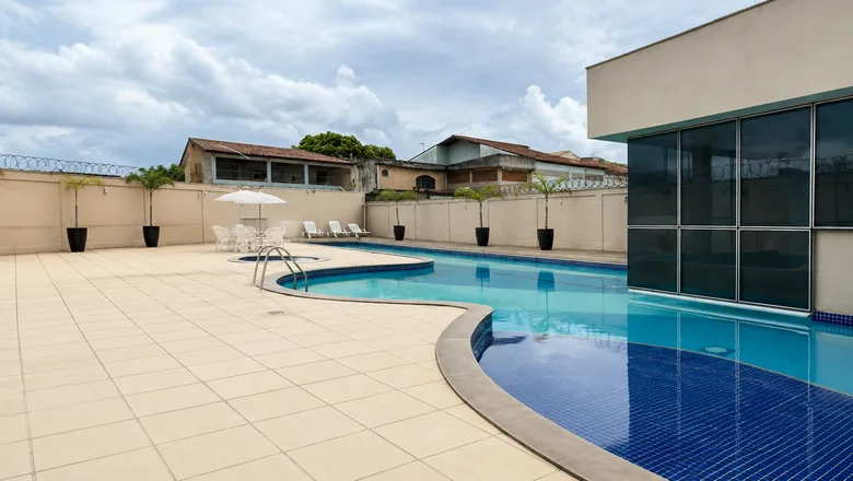 Piscina do Condomínio Vivenda Laranjeiras com espreguiçadeiras e salão de festas